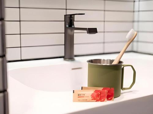 a toothbrush in a mug on a counter next to a sink at Harbour Bay Hotel in Hong Kong
