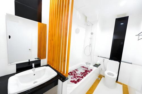 a bathroom with a tub and a sink and a toilet at GT Residence Hotel in Buriram