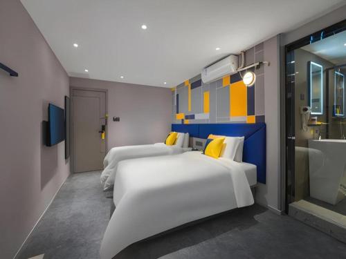 two beds in a hotel room with a bathroom at 7 Days Inn Xi'an Xijing Hospital Tonghuamen Metro Station in Xi'an