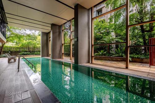 an indoor swimming pool in a house with windows at Palm Spring Condo Nimman - Deluxe 810 in Chiang Mai