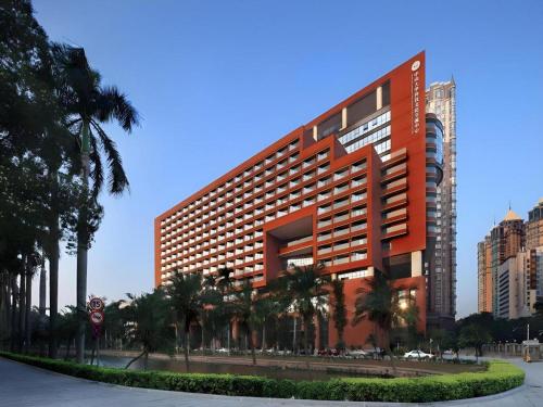 a large orange building with palm trees in front of it at SUN Yat-sen university Hotel and Conference Centre in Guangzhou