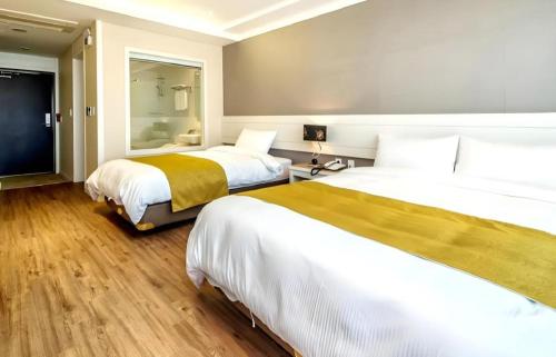 a hotel room with two beds and a television at Galaxy Hotel in Jeju