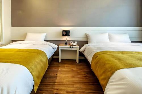 two beds in a room with a table between them at Galaxy Hotel in Jeju
