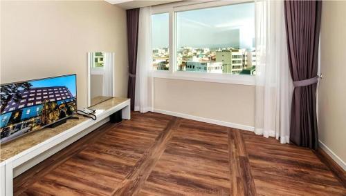 a living room with a tv and a large window at Galaxy Hotel in Jeju
