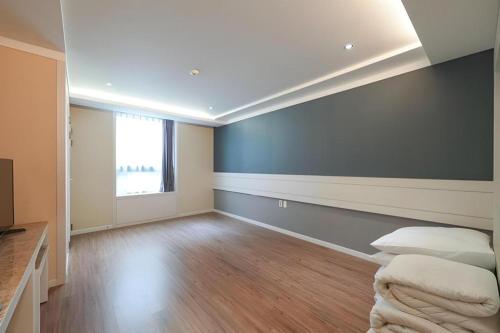an empty room with a bed and a window at Galaxy Hotel in Jeju