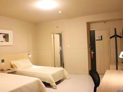 a hotel room with two beds and a door at Jinjiang Inn Quanzhou West Street Kaiyuan Temple in Quanzhou
