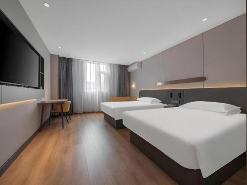 a hotel room with three beds and a flat screen tv at Jinjiang Inn Quanzhou West Street Kaiyuan Temple in Quanzhou