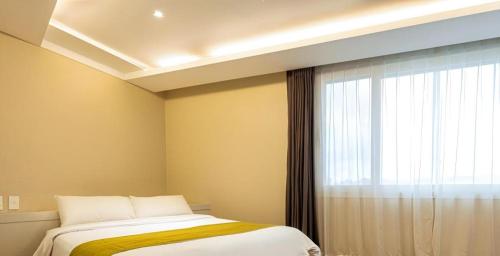 a bedroom with a bed and a window at Galaxy Hotel in Jeju