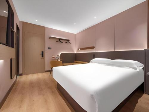 a bedroom with a large white bed and a desk at Jinjiang Inn Quanzhou West Street Kaiyuan Temple in Quanzhou