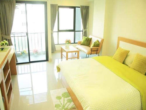 a bedroom with a bed and a couch and windows at Ipremium Sukhumvit 81 Hotel in Bangkok