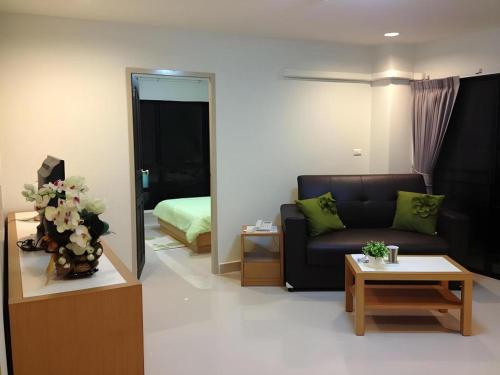 a living room with a couch and a bedroom at Ipremium Sukhumvit 81 Hotel in Bangkok