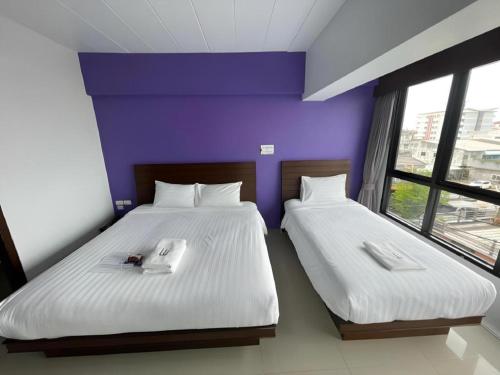 two twin beds in a room with a purple wall at Wsotel Hotel in Songkhla