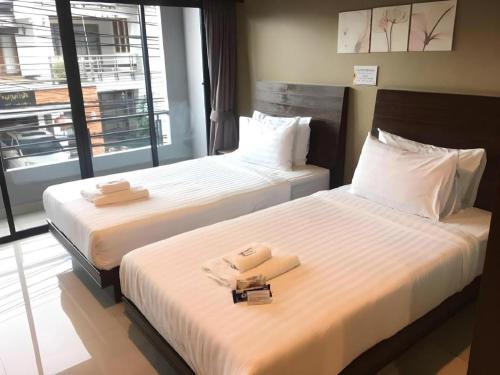 two beds in a hotel room with towels on them at Wsotel Hotel in Songkhla