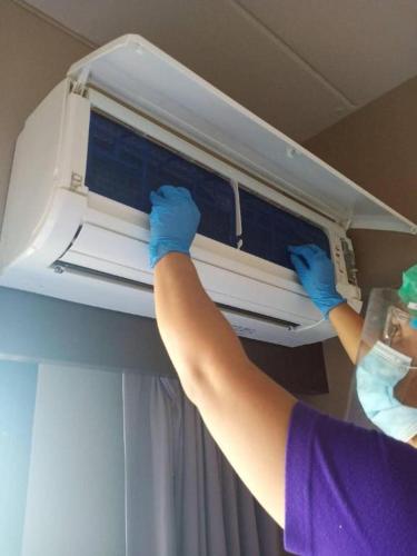 a person in blue gloves reaching into a microwave at Wsotel Hotel in Songkhla