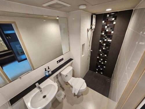 a bathroom with a sink and a toilet and a mirror at Wsotel Hotel in Songkhla