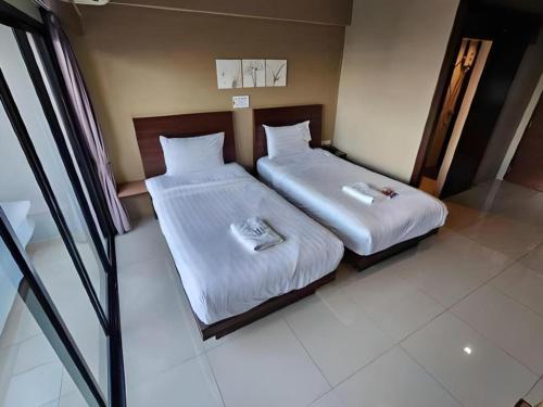 a bedroom with two beds with white sheets at Wsotel Hotel in Songkhla
