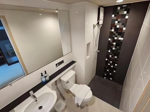a bathroom with a toilet and a sink and a mirror at Wsotel Hotel in Songkhla
