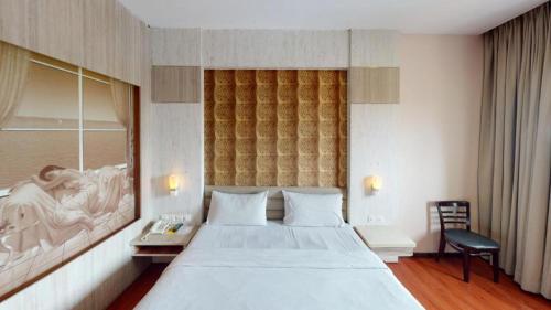 a bedroom with a large white bed and a desk at The Golden Bay Hotel Batam in Nagoya
