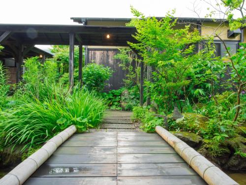 a garden with a wooden walkway and plants at Yurari Rokumyo in Yufuin