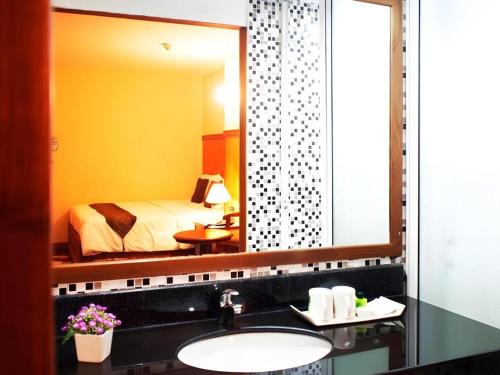 a bathroom with a sink and a large mirror at NH Elegant Hotel in Sakon Nakhon