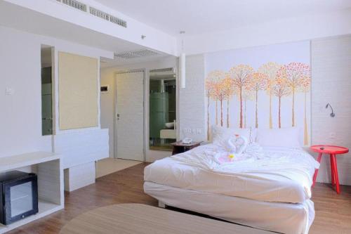 a bedroom with a bed with a tv and trees on the wall at Royal Bay Hotel Makassar in Makassar