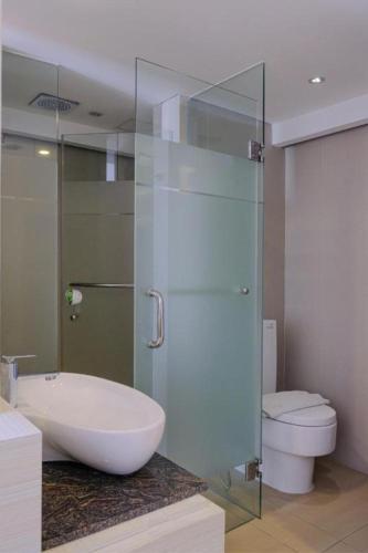 a bathroom with a glass shower and a toilet at Royal Bay Hotel Makassar in Makassar