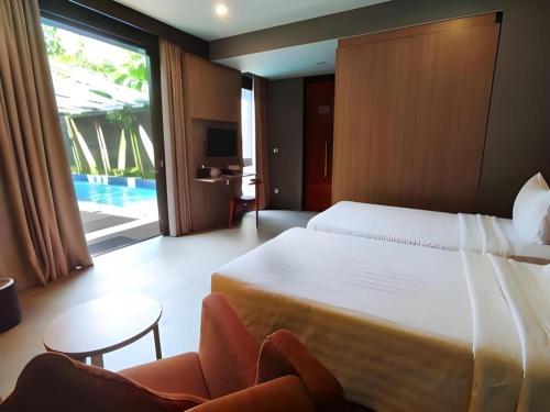 TanjungbungaにあるGammara Hotel Makassarのベッドと椅子とテレビがあるホテルの部屋