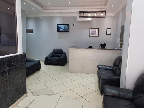 a waiting room with black leather chairs and a bar at Tudor House Hotel in Durban