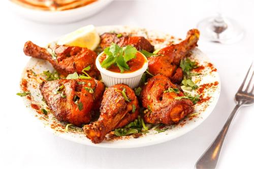 a plate of food with chicken wings and dipping sauce at Collection O Pearl Blue in Tājganj