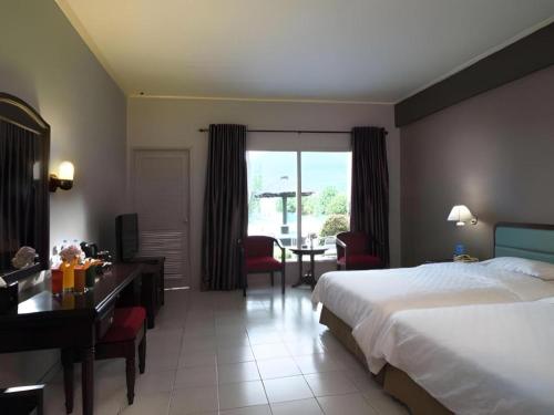 a hotel room with a bed and a desk and a table at Hotel Niagara Parapat in Parapat