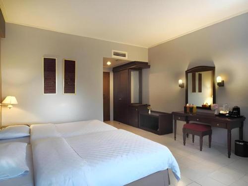 a bedroom with a large white bed and a desk at Hotel Niagara Parapat in Parapat