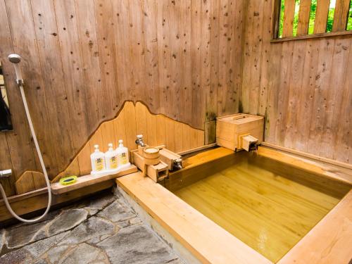 a wooden bathroom with a toilet in a wooden wall at Yurari Rokumyo in Yufuin