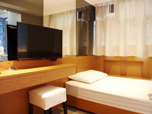 a bedroom with a bed and a flat screen tv at Acesite Knutsford Hotel in Hong Kong