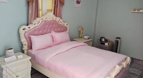 a bedroom with a pink bed with a white headboard at Chateau de Sangkhlaburi in Sangkhla Buri