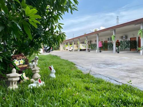 a group of rabbits in the grass in front of a building at Sweet Hug Hotel in Suphan Buri