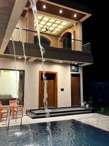 a swimming pool with a fountain in front of a house at BluSplash Private Pool Villa in Lakāwās