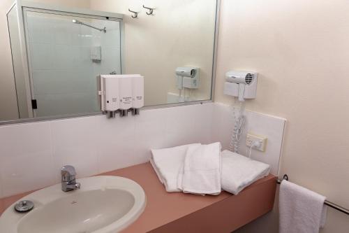 a bathroom with a sink and a mirror at White Lace Motor Inn in Mackay