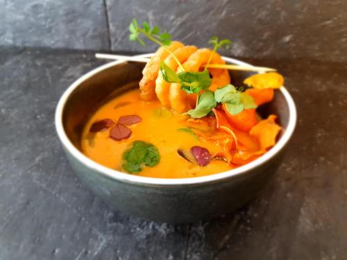 a bowl of soup with shrimp and greens on top at Tyrifjord Hotell in Vikersund