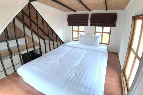 a large white bed in a room with windows at Chang Puak Resort Damnoen Saduak in Ratchaburi