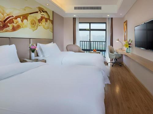 une chambre d'hôtel avec deux lits et une télévision à écran plat dans l'établissement Vienna Hotel Nanning Xiangsi Lake University Town, à Nanning