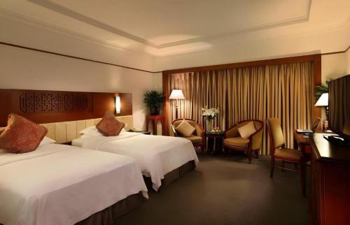 a hotel room with two beds and a desk at Capital Hotel in Beijing