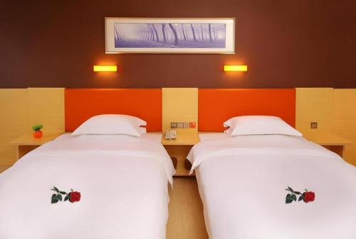 two beds in a room with orange and white at 7 Days Premium Nanjing Gaochun Beiling Road Branch in Gaochun