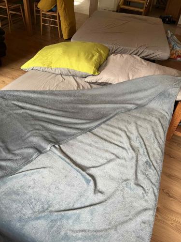a bed with a gray blanket and a yellow pillow at Historische Maisonettewohnung bis 10 Gäste, Magic Pass Belalp, Rosswald und mehr in Naters