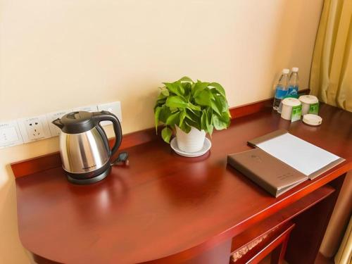 a desk with a tea kettle and a plant on it at GreenTree Inn Taizhou New District Hospital of Renmin Hospital Mingliu Express Hotel in Jiuligou