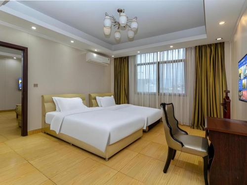 a bedroom with a large white bed and a desk at Jian Guo Grand Hotel in Vientiane