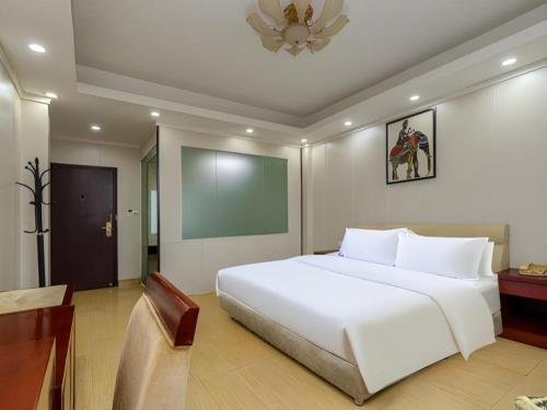 a bedroom with a large white bed and a table at Jian Guo Grand Hotel in Vientiane