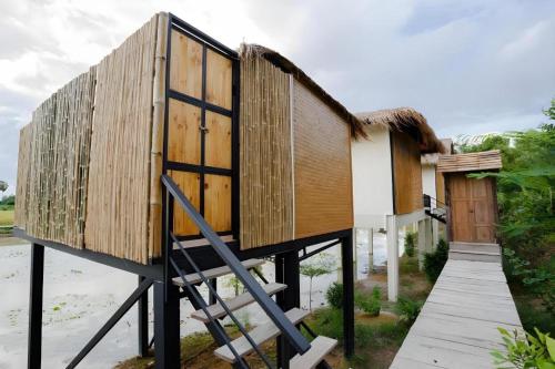 a small house with a thatched roof and a staircase at Nornnadubua in Uthai Thani