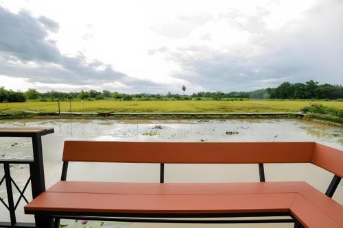 a bench sitting in front of a pond at Nornnadubua in Uthai Thani