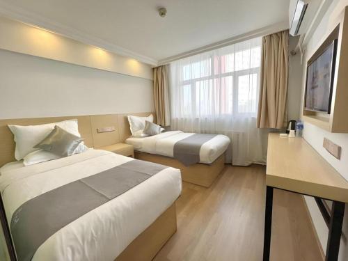 a hotel room with two beds and a window at GreenTree Inn Urumqi South Xinhua Road Hotel in Ürümqi