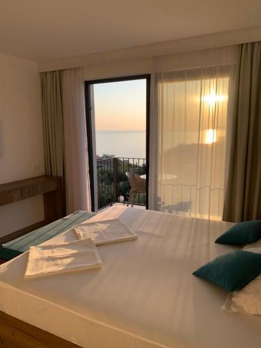 a bedroom with a large white bed with a large window at REZEVICI BOUTIQUE VILLA in Petrovac na Moru
